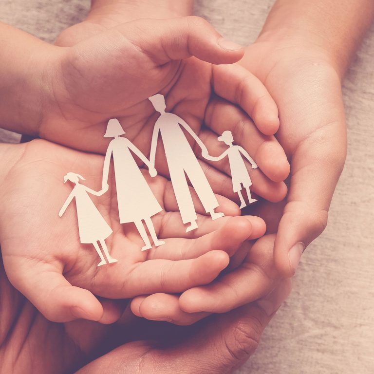 Hands holding paper family cutout, supporting families with pastoral care in distance education